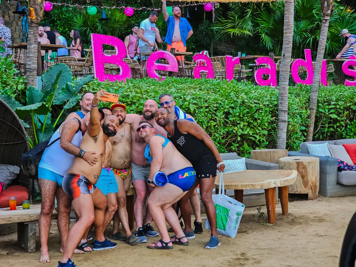 Guests taking a group selfie at Bearadise Beach in front of giant pink Bearadise letters