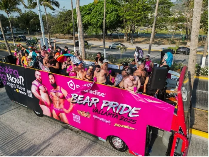 Our pink Bear Pride bus in the Vallarta Pride parade, guests on the top deck above the banner