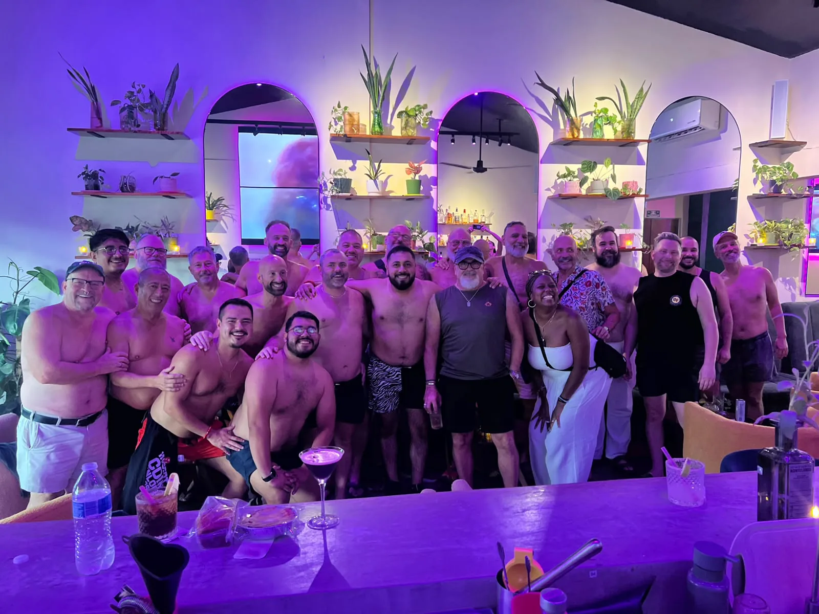 Un Tummy Tuesday a reventar: el grupo apretado en la barra, abrazados, bajo luces moradas.